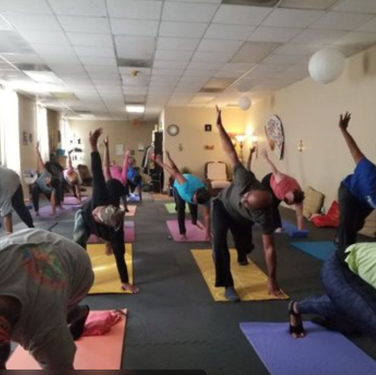 Yoga Hive Atlanta yoga class in session with diverse students practicing yoga poses in a warm, welcoming studio space centered on mindfulness, mobility, flexibility, stress relief, and community-focused holistic wellness.